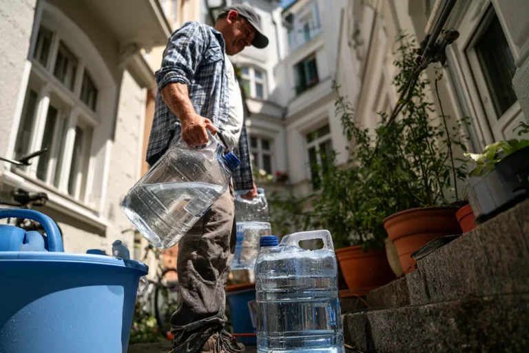 Mann trägt Wasserflaschen im Hof.